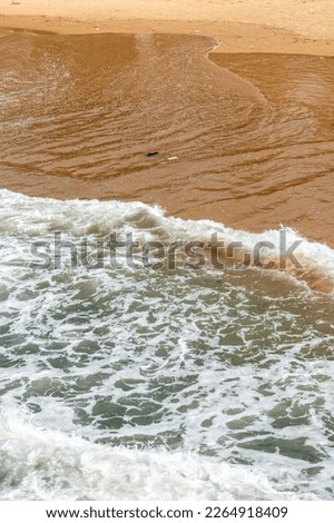 Abstract nature background of the aerial view of the waves of the sea hitting a beach in Goa.