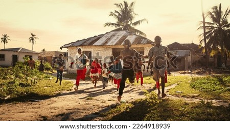 Group of African Little Children Running Towards the Camera and Laughing in Rural Village. Black Kids Full of Life and Joy Enjoying their Childhood and Playing Together. Little Faces with Big Smiles Royalty-Free Stock Photo #2264918939
