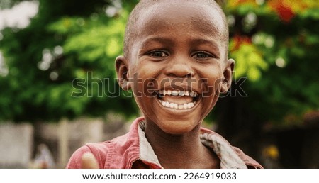 Close Up Portrait of an Expressive Authentic African Kid Laughing and Looking at the Camera Blurry Background. Happy Energetic Black Boy Full of Life Smiling Happily and Enjoying Life and Childhood Royalty-Free Stock Photo #2264919033