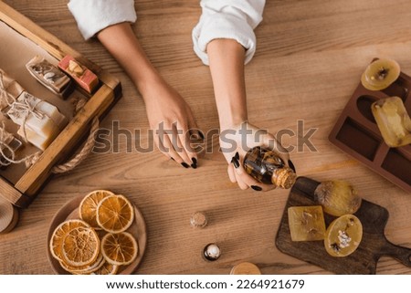 top view of cropped african american woman holding essential oil near homemade soap and dried orange slices in craft workshop Royalty-Free Stock Photo #2264921679