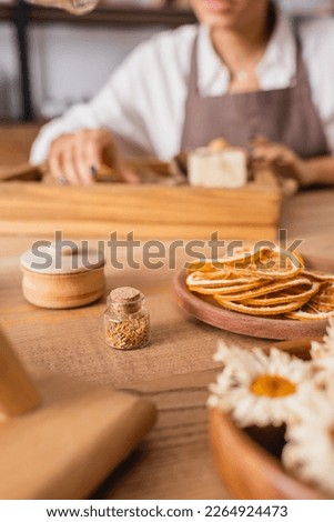 cropped view of african american woman near dried orange slices and camomiles on blurred foreground in craft workshop Royalty-Free Stock Photo #2264924473