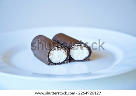 Close-up of a hungarian dessert called "Túró Rudi". The bar is composed of a thin chocolate-flavored outer coating and an inner filling of túró (curd).                               Royalty-Free Stock Photo #2264926129