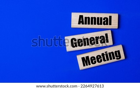 Three wooden blocks with the text AGM Annual General Meeting Royalty-Free Stock Photo #2264927613