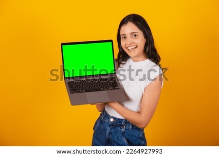 beautiful brazilian woman holding notebook, showing green screen.