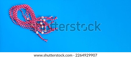 Bulgarian symbol of spring, many white and red martenitsa bracelets on blue banner background
