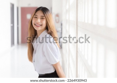 Portrait of cute Thai student in university student uniform. Young Asian beautiful girl standing smiling confidently at university.