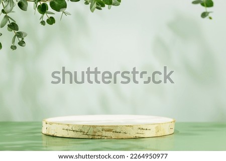 Wooden empty podium for presentation or advertising. Round product display on blue background with green eucalyptus leaves and shadows. Concept of scene stage for natural products or promotion sale