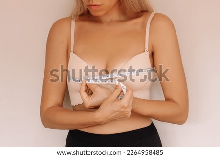 Cropped shot of young caucasian blonde slender woman measuring her measures the chest circumference with a centimeter isolated on a beige background. Diet, sport healthy lifestyle, wellness concept Royalty-Free Stock Photo #2264958485