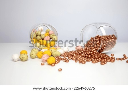 Chocolate colorful decorative eggs in a glass jar on a white background. Happy Easter. Front view