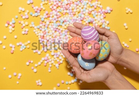 Happy easter Colourful of Easter eggs in hands on yellow background. Greetings and presents for Easter Day celebrate time. Flat lay ,top view.