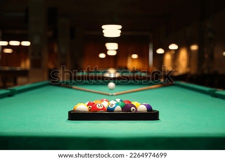 Plastic triangle rack with billiard balls and cues on green table indoors Royalty-Free Stock Photo #2264974699