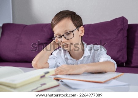 Young boy reading book at home. 
Education, childhood, homework and school concept.