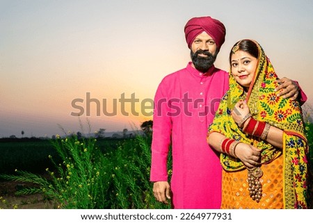 Portrait of Happy young Punjabi sikh farmer couple standing together at agriculture field. copy space.
