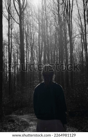 A black and white forest with a girl who's in color. 