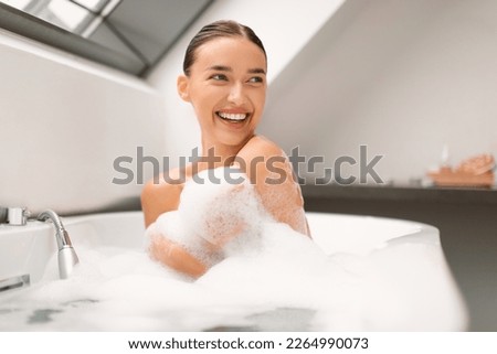 Smiling Lady Taking Relaxing Bath Looking Aside Sitting In Bathtub With Foam In Modern Bathroom At Home. Woman Bathing Enjoying Bodycare Routine. Beauty And Spa Concept Royalty-Free Stock Photo #2264990073