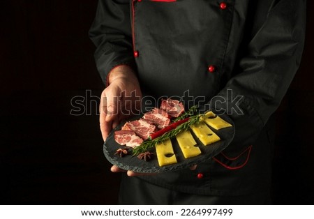The chef is holding a serving plate with a ham and cheese appetizer. The concept of serving food by a waiter in a restaurant. Free space for recipe or menu