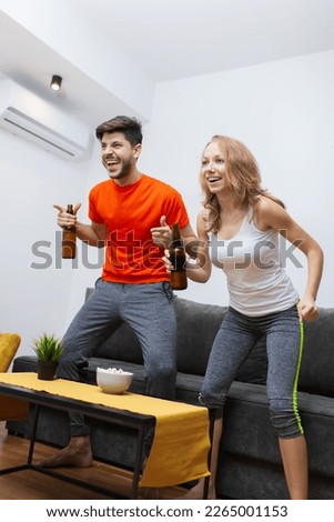 couple at home watching the game on tv having beer cheering and yelling