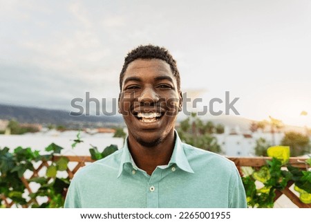 Happy young African man having fun smiling in front of camera on house patio