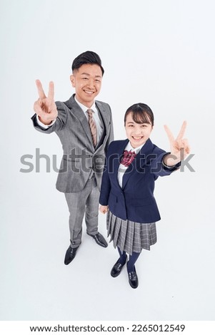 A man and a high school girl in a suit doing a peace sign         