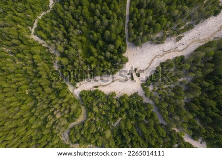 Drone photography of mountain river flowing through forest and hike trail during summer day