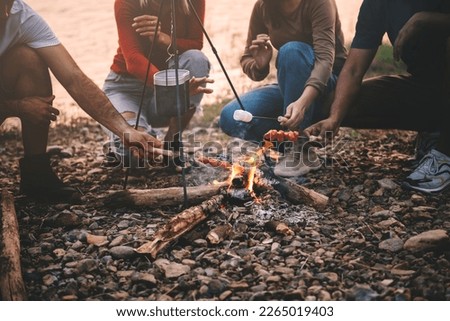 Close up photo of friends roasting marshmallows and bbq over the fire, friends spending time together at camp yard.