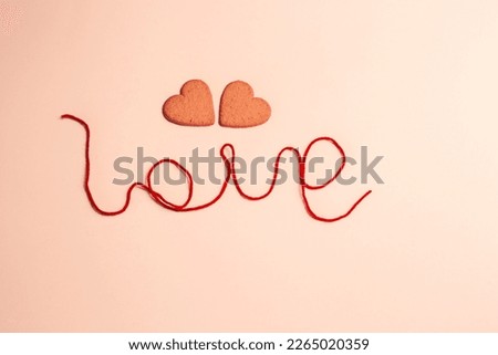 hearts behind the "love" word on soft pink background, isolated, copy space 