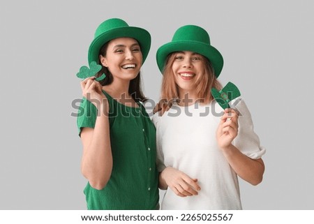 Young women with paper hat and clover on light background. St. Patrick's Day celebration