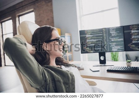 Photo of smiling positive lady hacker wear eyeglasses arms hands behind head having rest indoors workplace workstation