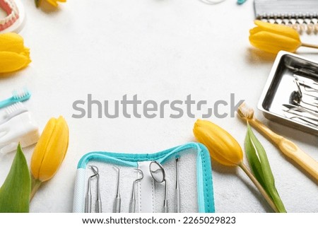 Frame made of dentist's tools and tulips on white background, closeup. Hello spring