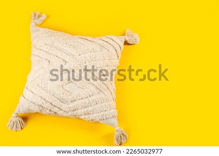 Light decorative pillow on yellow background Royalty-Free Stock Photo #2265032977