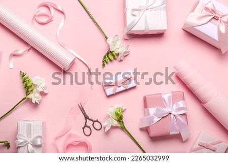 Composition with gift boxes, wrapping paper and freesia flowers on pink background. Women's Day celebration Royalty-Free Stock Photo #2265032999