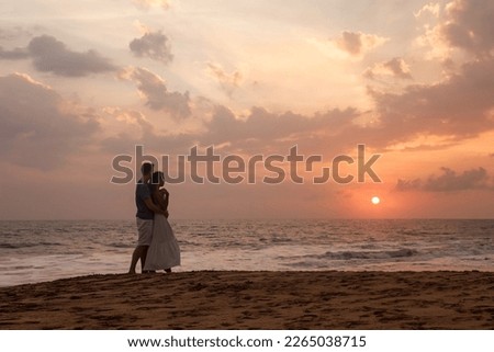 Silhouettes lovely happy couple enjoying honeymoon summer on tropical sandy beach at sunset background. Man and woman young couple in love hugging. Family travel vacation concept. Copy ad text space