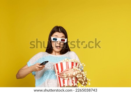 woman with remote control holding bucket of popcorn