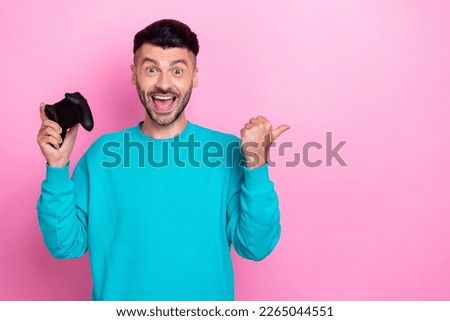 Photo of young attractive funny man have fun hold gamepad direct finger empty space excited steam games sale isolated on pink color background Royalty-Free Stock Photo #2265044551