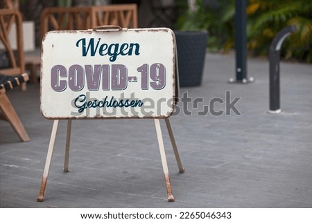 Outdoor open sign with written in it in German "Wegen COVID-19 Geschlossen" meaning in English "Closed due to COVID-19".