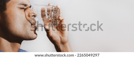 Sad young man and looking with drink in his hand on a gray background and space for text, concept of problems with alcoholic beverages, depression, alcoholism.