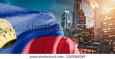 Liechtenstein national flag cloth fabric waving on beautiful buildings background.