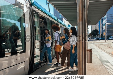 A group of university students going home after classes at school are entering the public transportation train. Royalty-Free Stock Photo #2265069985