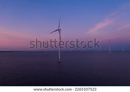 Aerial drone view of a park of offshore wind turbines in the sea at sunset in the Netherlands. Green and renewable energy concept. High quality 4k footage