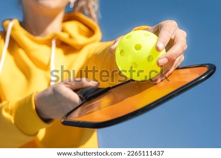 Pickleball paddle and yellow ball close up, woman playing pickleball game, hitting pickleball yellow ball with paddle, outdoor sport leisure activity Royalty-Free Stock Photo #2265111437