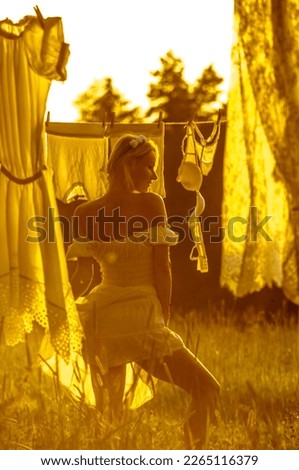 Blonde in white drying laundry at sunset