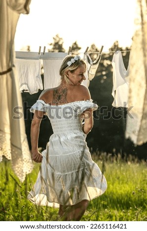 Blonde in white drying laundry at sunset