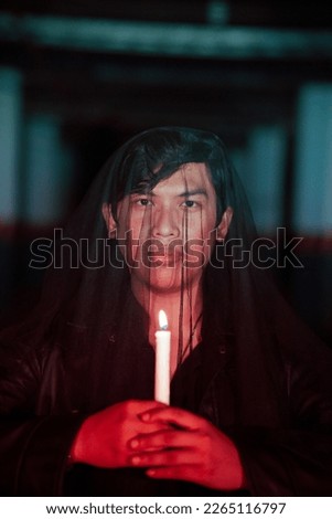 a man dressed all in black holding a candle when going to a cemetery to perform rituals at night