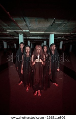 a group of devil worshipers lined up together while holding a candle in the old wake when the ritual will be carried out at night Royalty-Free Stock Photo #2265116901