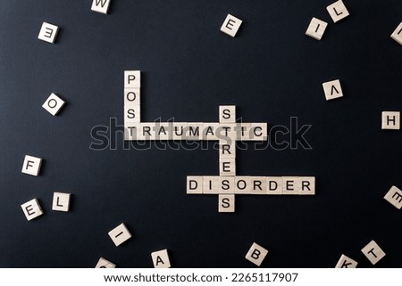 Words Post Traumatic Stress Disorder on wooden blocks on black background. Minimal concept PTSD