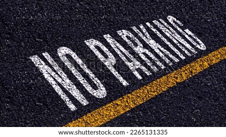 No Parking written and yellow line on the road in middle of the asphalt road, No Parking word on street.