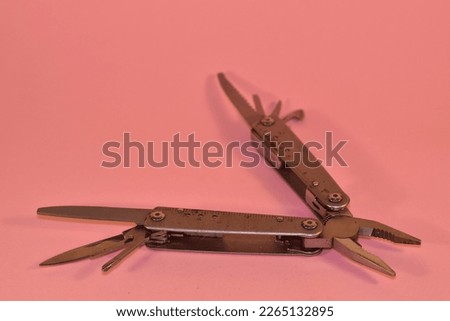 Multi tool pliers on a pink background 