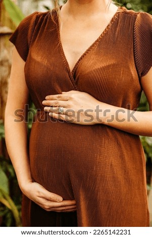 Expecting mom during her maternity photoshoot at an indoor greenhouse.