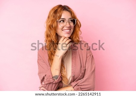 Young caucasian woman isolated on pink background With glasses and thinking while looking up Royalty-Free Stock Photo #2265142911