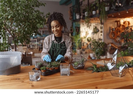 Professional woman florist takes care of seedlings in floral studio. Blurred background